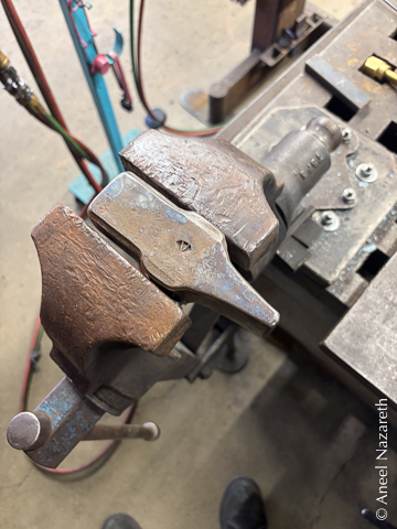 The hammer head held in a vise. It has some rough scale on the surface